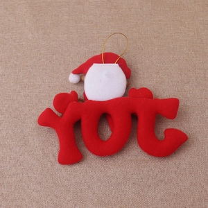 Close-up of red velvet JOY letter ornament featuring a Santa Claus face and gold hanging cord