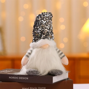 Detail of a Christmas gnome with silver sequined hat and plush white beard on a cozy desk