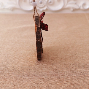 Side view of rustic round wood gnome pendant with red plaid bow and natural texture