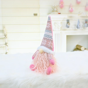 Close-up of a pink plush Christmas gnome doll with snowflake patterned knit hat and soft faux fur