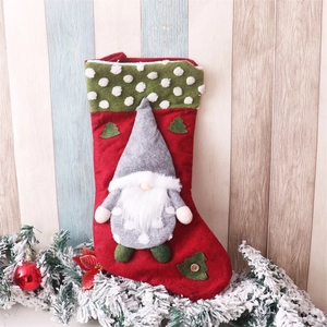 Detail of red Christmas stocking with gnome figurine and decorative pine tree patterns