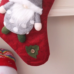 Detail of red felt Christmas stocking featuring a 3D gnome doll and a green tree patch