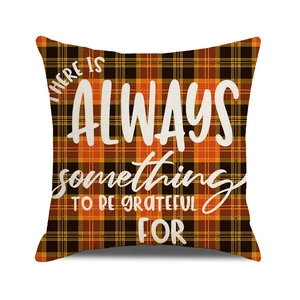 Macro shot of orange and black plaid pillow cover with white grateful quote typography