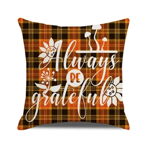 Close-up of orange plaid cushion cover with Always BE grateful text and floral details
