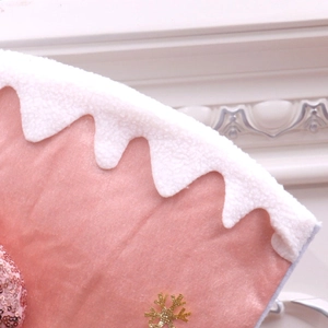 Close-up of pink velvet Christmas stocking with white fleece trim and golden snowflake