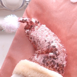 Detailed view of pink sequined Christmas hat with white faux fur trim and shiny pom-pom