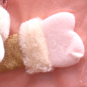 Detail showing pink plush heart accessory with cream faux fur and golden ribbon trim