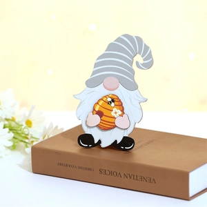 Détail d'un gnome en bois sur le thème des abeilles avec chapeau rayé sur un livre