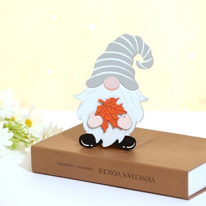 Vue détaillée d'un gnome d'automne en bois avec feuille d'érable sur un vieux livre