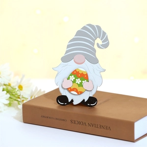 Détail d'un gnome de Pâques en bois avec un œuf marguerite posé sur un livre