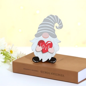 Détail d'un gnome en bois tenant un cœur rouge LOVE posé sur un livre ancien