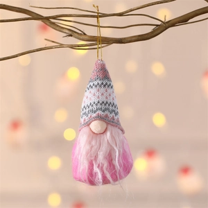 Pink knitted Christmas gnome ornament with white beard hanging on a natural branch
