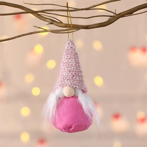 Close-up of pink sequined gnome ornament hanging on branch with warm festive lighting