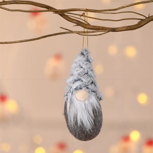 Detail of plush Christmas gnome ornament hanging on a branch with festive bokeh lights