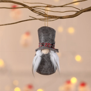 Close-up of a grey gnome plush hanging from a branch with warm festive bokeh lights