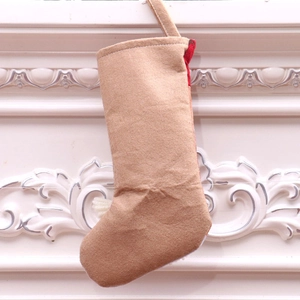 Detail of khaki felt Christmas stocking with red lining hanging on white fireplace