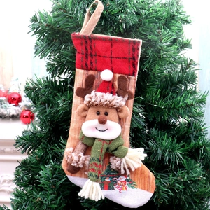 Detail of Christmas stocking with 3D reindeer and plaid cuff hanging on a tree
