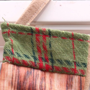 Detail of Christmas stocking with green plaid trim and red-brown woven texture