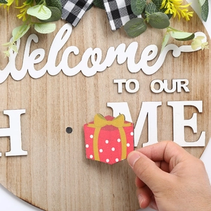 Détail d'une main fixant un accessoire de cadeau au panneau de porte Welcome Home