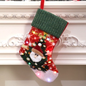 Large LED glowing Christmas stocking with Santa and Welcome text hanging on a white fireplace