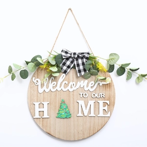 Détail d'une plaque de bienvenue en bois avec motif sapin et nœud en tissu à carreaux