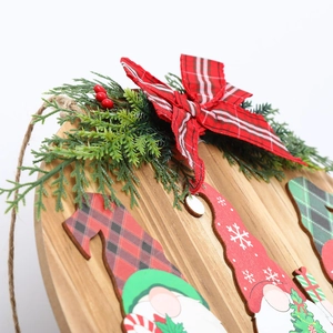 Detail of wooden Christmas door sign with gnome motifs, faux pine and red plaid bow