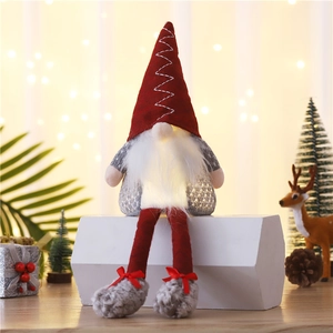 Glowing Christmas gnome plush toy with red knitted hat and warm light on a festive desk