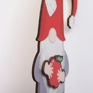 Detail view of wooden Christmas gnome ornament with red hat and a red apple