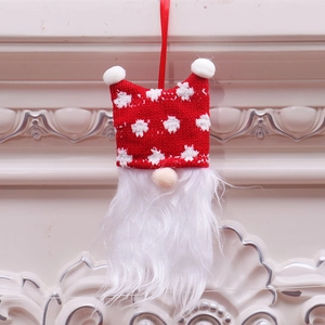 Detail of a Christmas gnome ornament featuring a red knit hat with white stars and plush balls