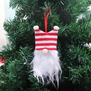Detail of a Christmas gnome ornament with striped hat hanging on a festive tree