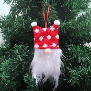 Close-up of a Christmas gnome ornament with red snowflake hat on a green Xmas tree