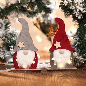 Détail de gnomes de Noël lumineux LED avec chapeaux en feutre sur branches de pin