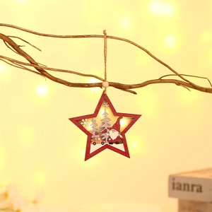 Illuminated wooden star ornament with Santa and pine tree hanging on a rustic branch