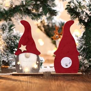Détail d'un gnome de Noël lumineux à LED en bois avec bonnet rouge et boîtier à piles arrière