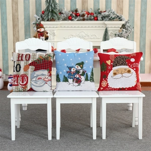 Three festive Christmas cushion covers with Santa and snowman patterns on white chairs