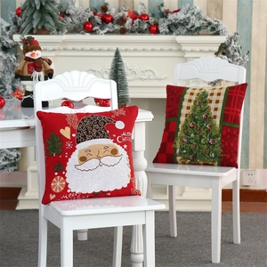 Detail of Christmas pillow cases with Santa embroidery on an elegant white chair