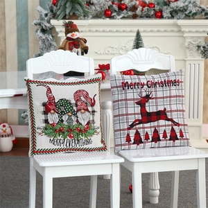 Close-up of Christmas gnome and reindeer cushion covers on white chairs with festive decor