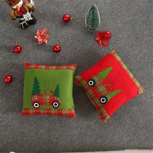 Detail of velvet embroidered Christmas pillows featuring red truck and tree motifs