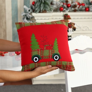 Detail of red velvet Christmas pillow with embroidered vintage truck and tree motif