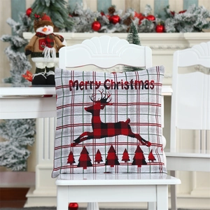 Detail of Christmas pillow cover with reindeer, tree silhouette and red plaid fabric