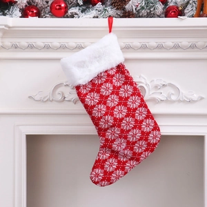 Large knitted red Christmas stocking with white snowflake patterns hanging on a fireplace