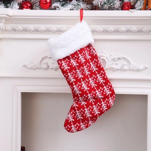 Knitted red and white Christmas stocking with snowflake pattern hanging on a white fireplace