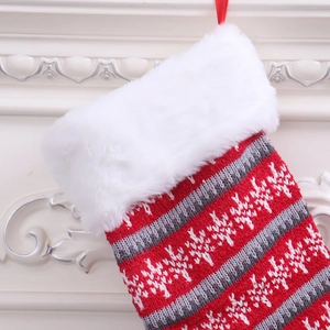 Detailed view of red knitted Christmas stocking with white snowflake patterns and plush fur cuff