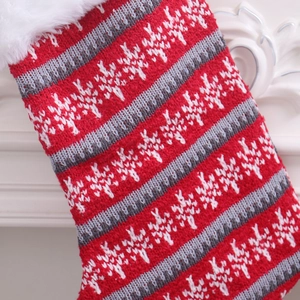Close-up of knitted Christmas stocking with red and grey stripes and white faux fur cuff
