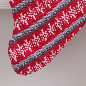 Macro shot of knitted Christmas stocking with red and white stripes and snowflake patterns