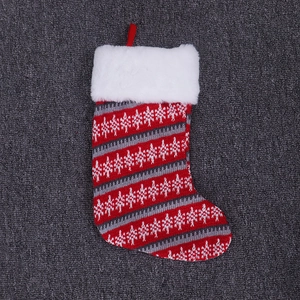 Detail of red and grey knitted Christmas stocking with snowflake pattern and plush white fur cuff