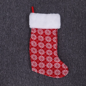 Close-up of red knitted Christmas stocking with white snowflake patterns and plush cuff