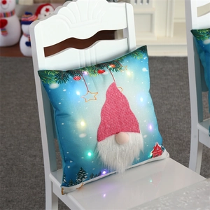 Close-up of LED glowing Christmas gnome pillow with blue snow scene and red knitted hat