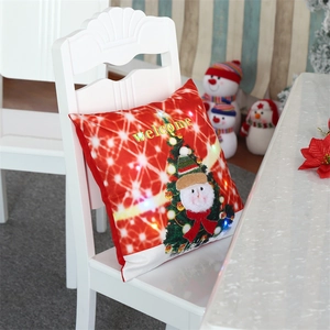 Close-up of LED glowing Christmas pillow cover with snowman and festive tree on chair