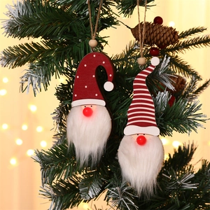 Close-up of glowing nose on wooden Christmas gnome ornaments hanging on a tree branch